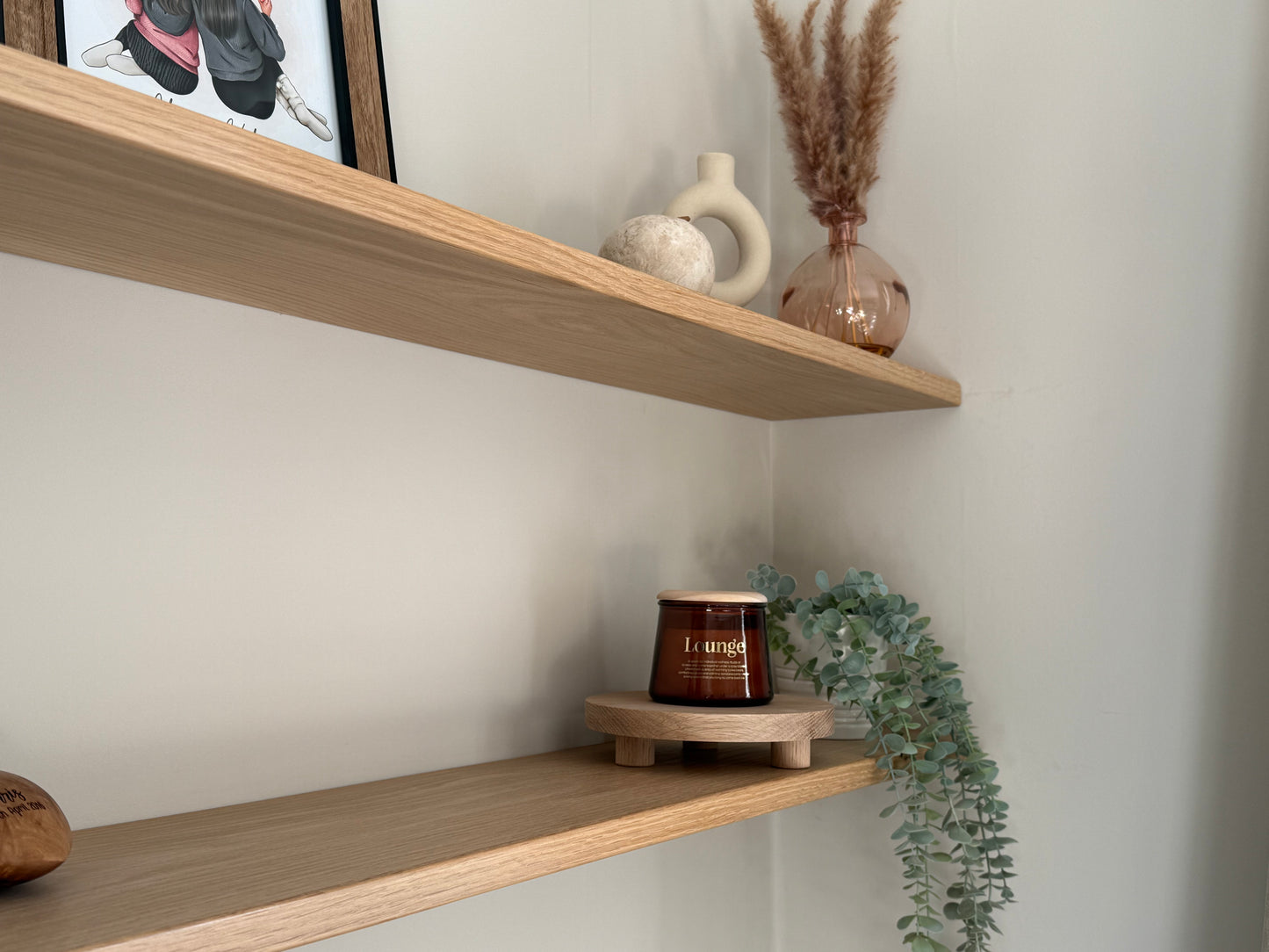 Wooden shelves with decorative items including a riser stand to display items against a neutral wall