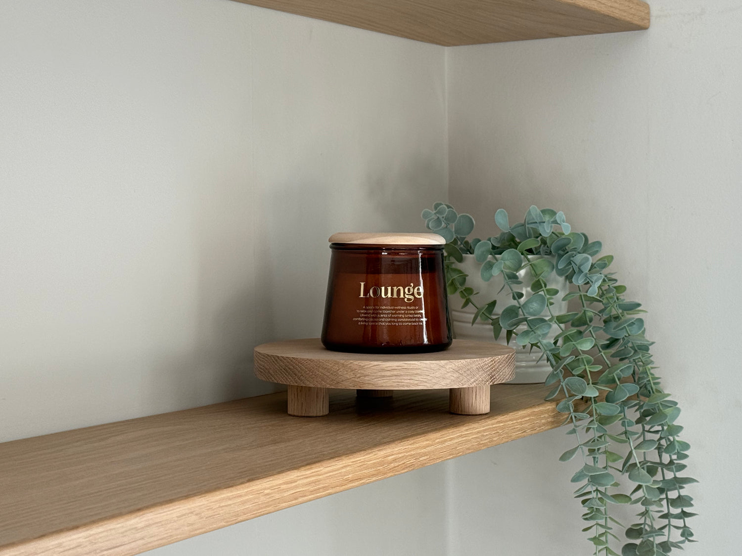 Riser table displaying a candle on a wooden shelf with a plant