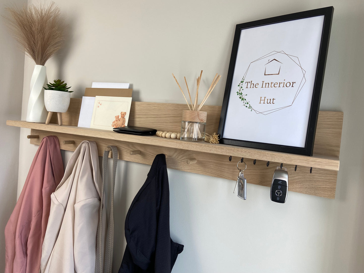 Oak organiser shelf with wooden pegs and hooks wall mounted displaying decorative items.