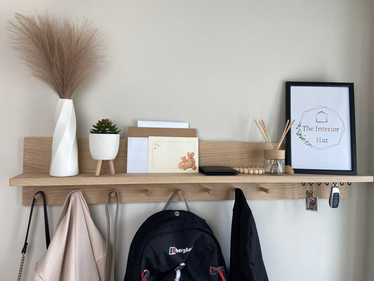 Handcrafted oak organiser shelf with wooden pegs and hooks displaying a plant and picture frame, letters ,coats, bags, and keys