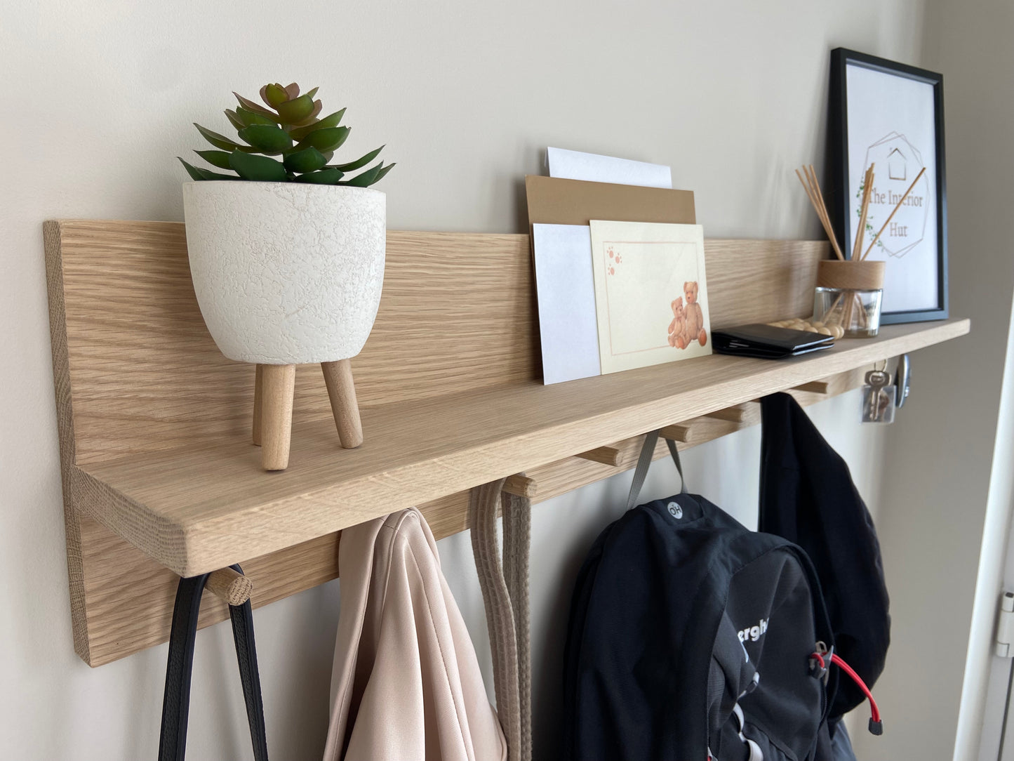 Oak organiser shelf with wooden pegs and hooks wall mounted displaying decorative items.