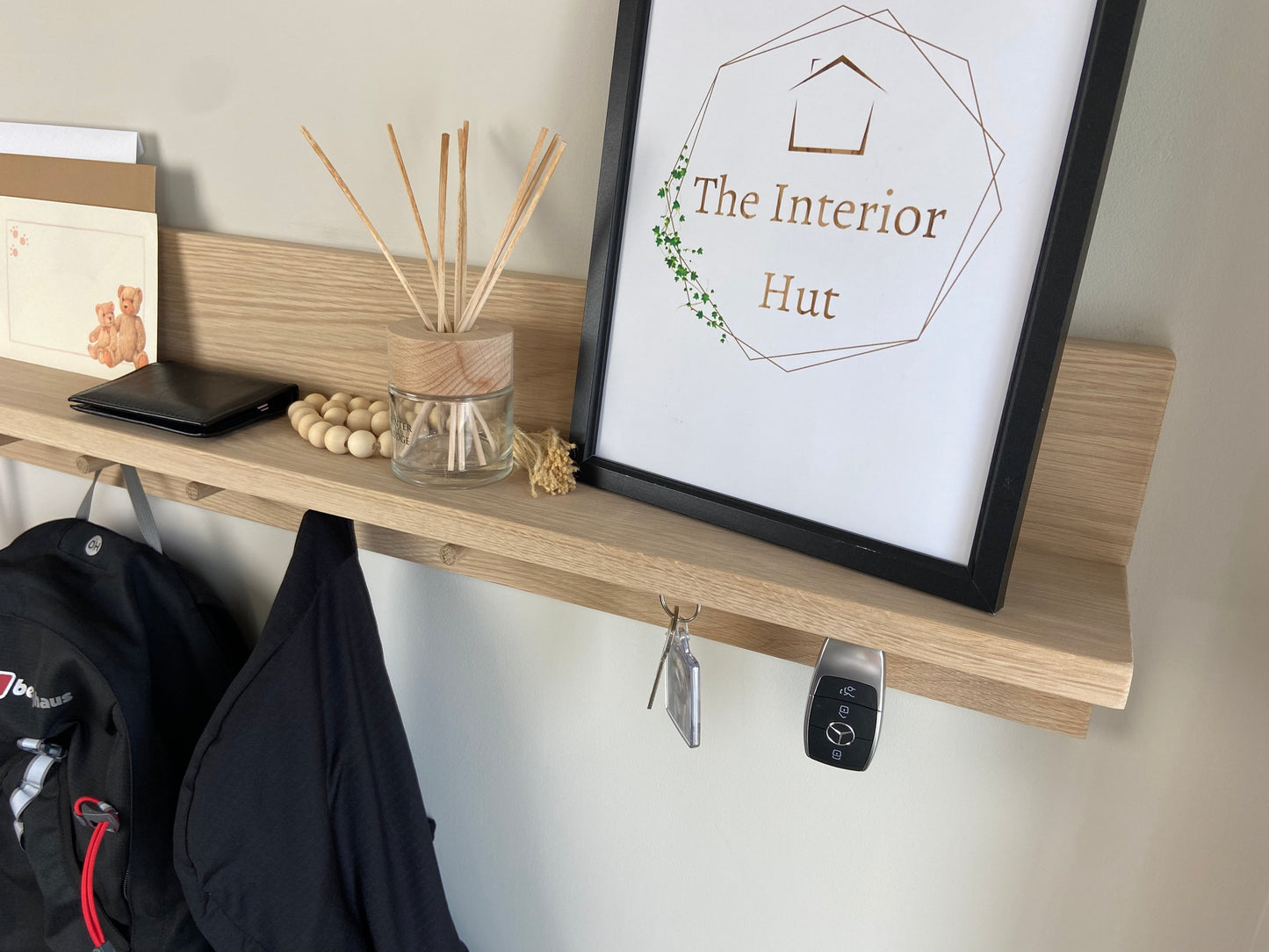 Close up of oak organiser shelf with wooden pegs and hooks wall mounted displaying decorative items.