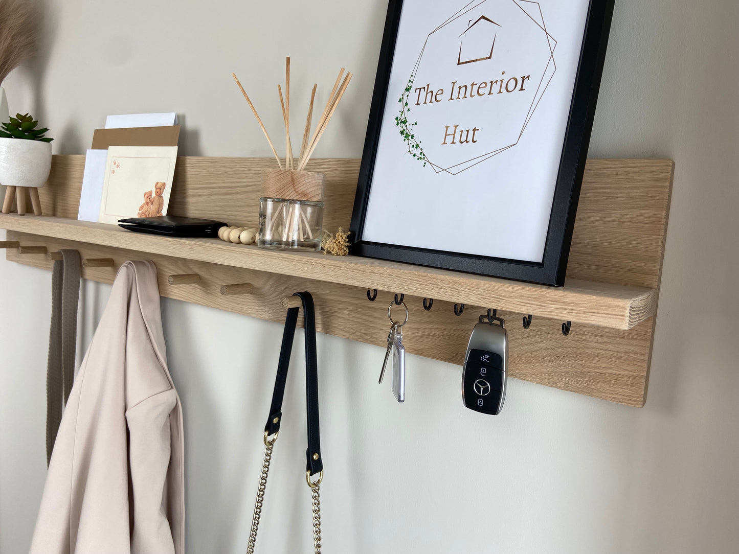 Close up of oak organiser shelf with wooden pegs and hooks wall mounted displaying decorative items.