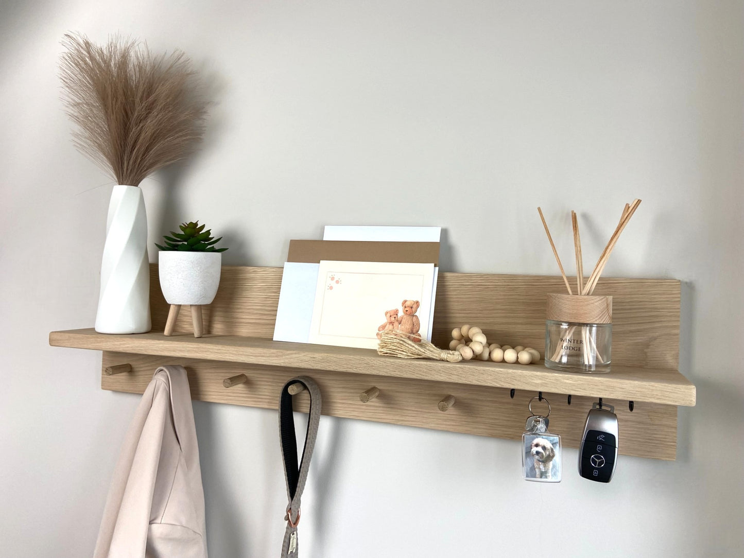 Medium oak organiser shelf with wooden pegs and hooks wall mounted displaying decorative items.