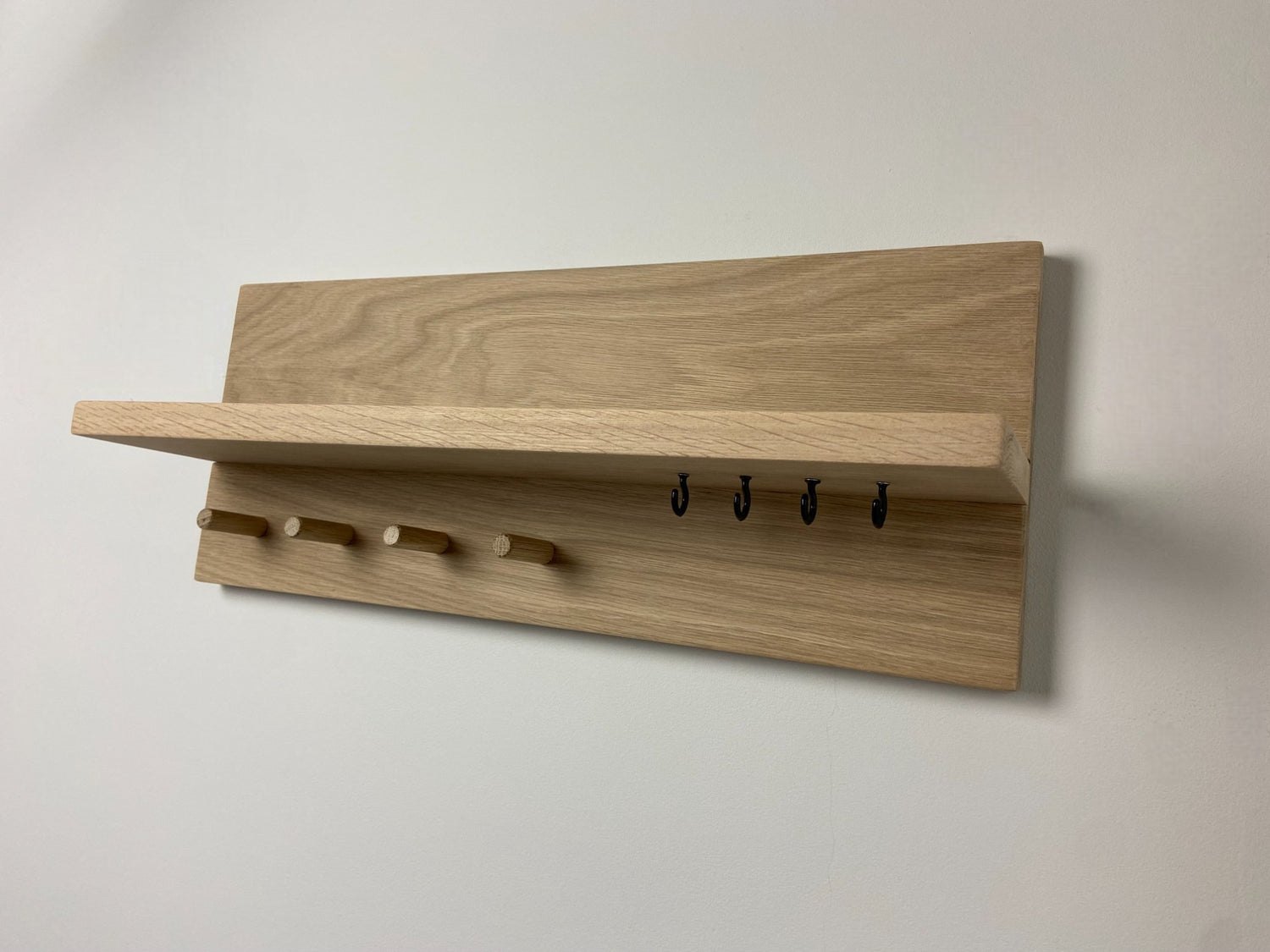 Small oak organiser shelf with wooden pegs and hooks wall mounted.