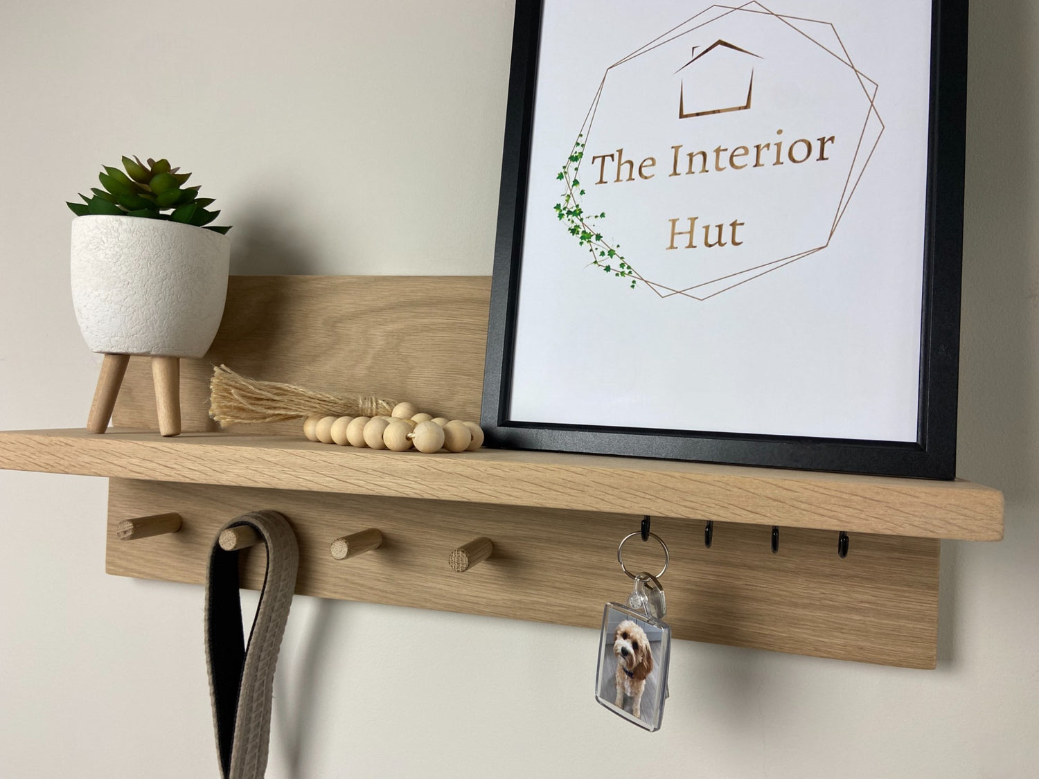 Small oak organiser shelf with wooden pegs and hooks wall mounted displaying decorative items.