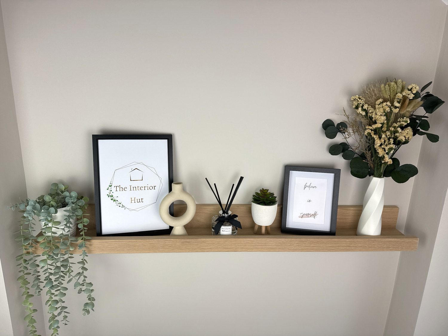 Handmade oak picture shelf with no wax finish, securely mounted on a plasterboard wall, holding photo frames and small décor items.