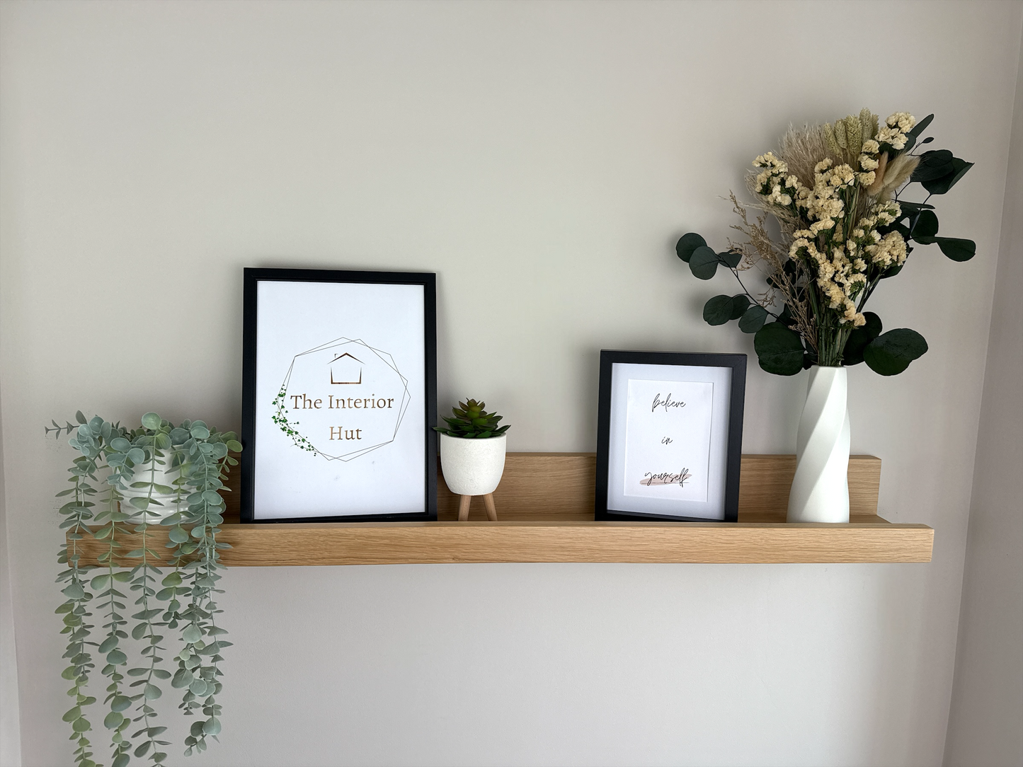 Handmade oak picture shelf with a Light wax finish, securely mounted on a plasterboard wall, holding photo frames and small décor items.