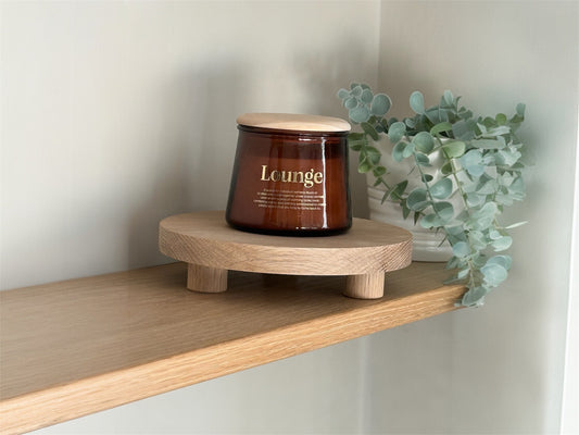 Oak stand displaying a candle beside a plant on a shelf